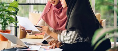 Genç, gülümseyen, mutlu, Asyalı Müslüman bir kadın dizüstü bilgisayarını kullanarak rahatlıyor ve evde video konferansı yapıyor. Ev konseptinden çalışma.