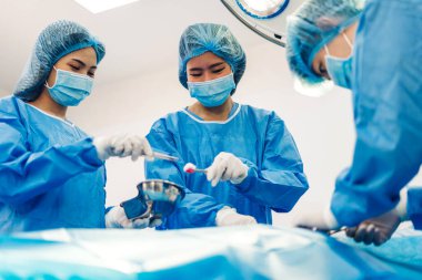 Profesyonel anestezi uzmanı doktor tıp ekibi ve asistanı modern hastane acil servisinde cerrahi ekipmanla jinekolojik ameliyata hazırlanıyor.
