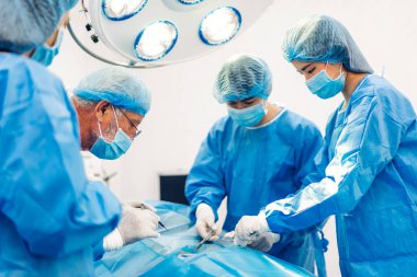 Profesyonel anestezi uzmanı doktor tıp ekibi ve asistanı modern hastane acil servisinde cerrahi ekipmanla jinekolojik ameliyata hazırlanıyor.