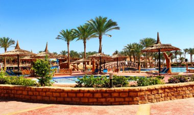 Havuzun arka planında plaj şemsiyeleri ve şezlonglar. 