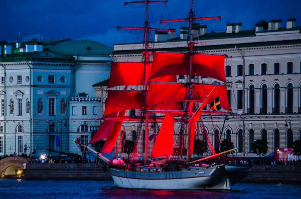A ship with scarlet sails is on the river against the night city