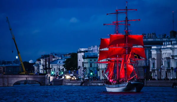 A ship with scarlet sails is on the river against the night city