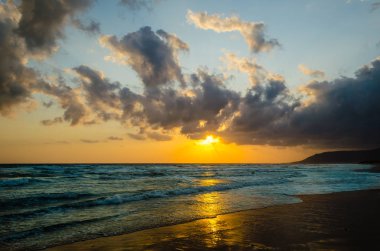 Deniz, haddeleme sakin dalgalar, ufuk Sunrise orange, skay turuncu ve mavi, bulutlar gri ve pembe.