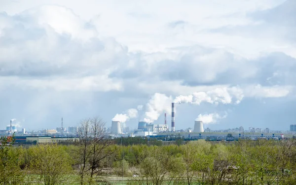 Büyük bir şehirde ısı istasyonu bulutlu bir gökyüzüne karşı atmosfere duman yakar