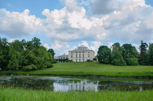 Eski Saray bir gölet ve mavi gökyüzü ve beyaz bulutlar karşı ağaçlarla çevrili yeşil bir çayır önünde bir tepe üzerinde duruyor