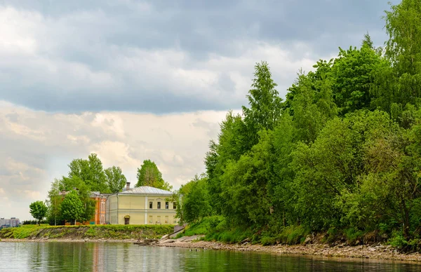 İki küçük taş evler - bulutlu gökyüzüne karşı orman yeşil masif çevrili nehrin Kıyısında sarı ve turuncu.