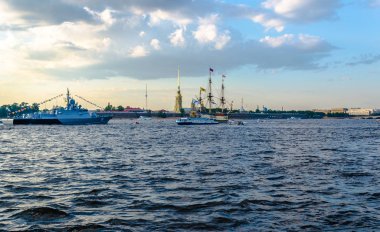 Antik yelken ve modern savaş gemileri mavi gökyüzü ve bulutlar karşı antik bir taş kalenin arka plan üzerinde geniş bir nehrin sularında demirlemiş.