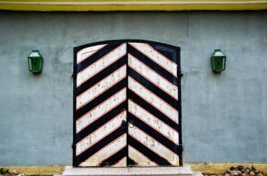 Eski ahşap kapılar gri bir duvara karşı kenarlarında fenerler ile siyah ve beyaz boyalı