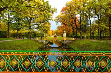Altın sonbahar dekorasyonunda ağaçların arka planına karşı Çin tarzında desenli köprüler ve taraçalar.