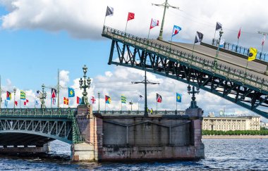 Köprünün kemerlerini indiriyorum, bayramın onuruna renkli bayraklarla süslenmiş mavi gökyüzü ve bulutların arka planına karşı