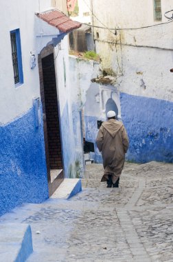 : Chefchaouen, Morocco - 17 Ocak 2010: Chefchaouen antik şehir Fas, mavi Medine yürürken Fas bornoz giymiş kimliği belirsiz adam.