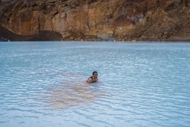 Genç kadın Viti volkanik krater Askja caldera, jeotermal gölün mavi sıcak suda banyo alır. İzlanda'nın Central Highlands.