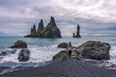 Kız genç deniz kıyısı Reynisdrangar bas için karşı karşıya yaklaşıyor