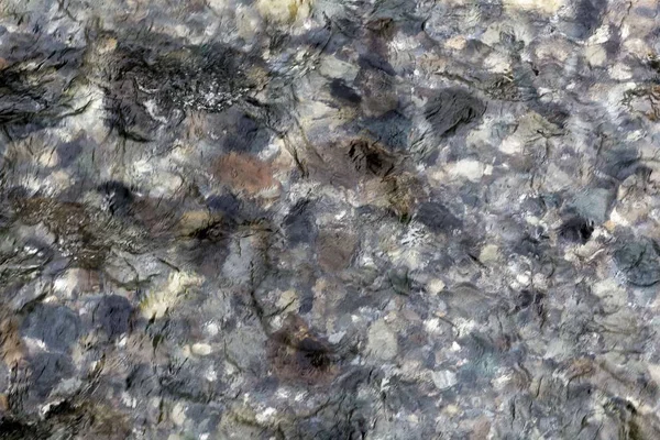 Wasseroberfläche eines klaren Gebirgsflusses mit Steinen. — Stockfoto