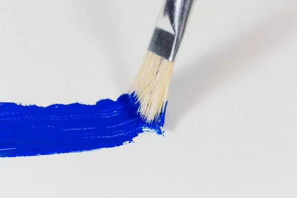 Pinsel mit blauer Farbe auf Leinwand-Hintergrund — Stockfoto