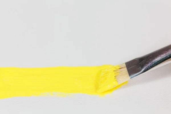 Štětec se žlutou barvou na pozadí plátna — Stock fotografie