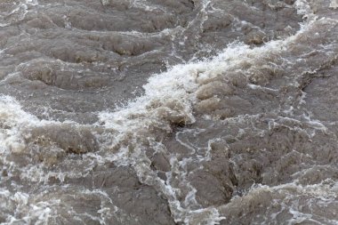 Köpüren kahverengi ve kirli su yüzeyi.