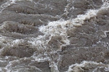 Köpüren kahverengi ve kirli su yüzeyi.