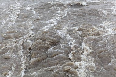 Köpüren kahverengi ve kirli su yüzeyi.