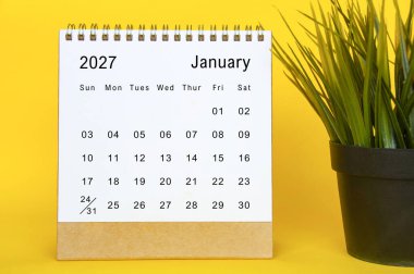 Ocak 2027 basit masaüstü kurulumu, canlı sarı kenarları ve yanında saksı bitkisi olan takvim sayfası