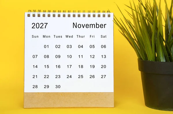 Minimalist beyaz arkaplana sahip sarı aksanlı masaüstü çerçevesi için Kasım 2027 takvim şablonu