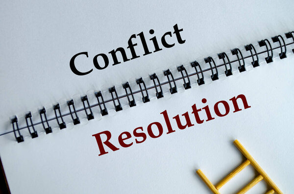 Conflict Resolution, Notepad with the bold words Conflict Resolution written across its white lined sheet on a desk
