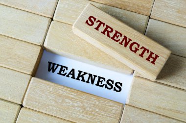 Strength and weakness text written on wooden blocks illustrating balance and self-assessment in growth