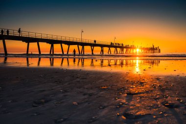Glenelg Beach İskelesi günbatımı Güney Avustralya'da yürüyen insan siluetleri