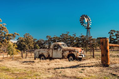 Kapunda, Güney Avustralya - 17 Haziran 2017: Paslı Holden Fj Ute ve vintage Kookaroo yel değirmeni otoyolu girişinden çiftlik yakınındaki ekranda