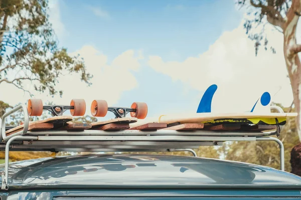 Skateboard dan papan selancar di rak atap mobil — Stok Foto