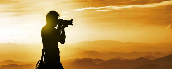 Silueta de un fotógrafo de mochilero con capa de montañas — Foto de Stock