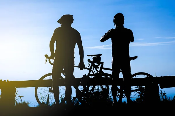 Ciclista com uma silhueta de bicicleta no fundo céu por do sol — Fotografia de Stock