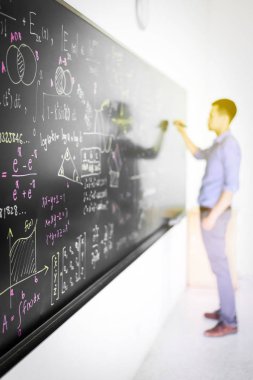 İşadamı kara tahtada matematik denklemini çözmeye çalışıyor 