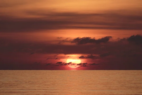 Gros soleil rouge orangé et nuages noirs — Photo