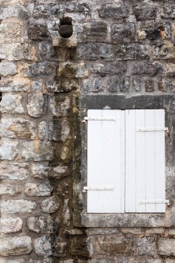 Eski bir taş kale duvarında kapalı beyaz panjurlar