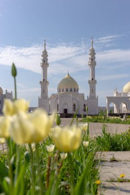 Güneşli bir bahar gününde Bulgarların beyaz camii sarı lalelerin arka planına karşı odak dışı