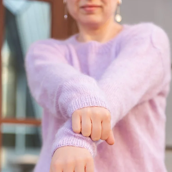 Weibliche Hände aus nächster Nähe Blick auf rosa Strickpullover Hintergrund. — Stockfoto