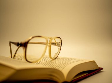 Açık bir kitap klasiğinde duran kırık gözlükler.