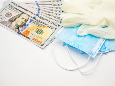 100 dolarlık banknotlar ve tek kullanımlık yüz maskesi ve eldiven gibi tıbbi malzemeler.