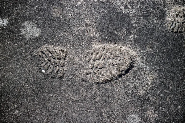 Shoeprint imprinted on gray asphalt.