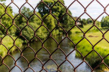 Nehir ve yeşil metal çit arkasında. Doğa kavramının erişilememesi.