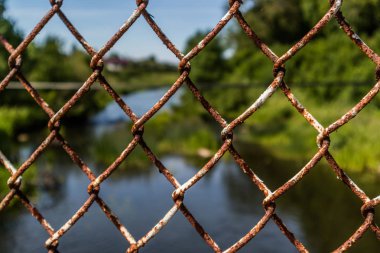 Nehir ve yeşil metal çit arkasında. Doğa kavramının erişilememesi.