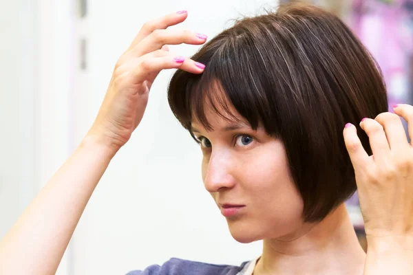 Güzel ve genç birbayan gri saç hakkında endişeleniyor.