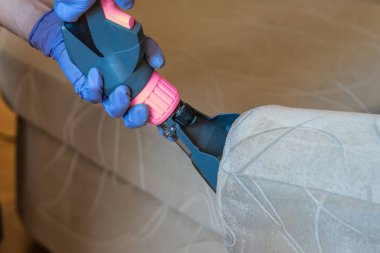 Kapitone kanepe profesyonel ayıklama yöntemi ile temizlik kimyasal closeup. Adam meme tutuyor.