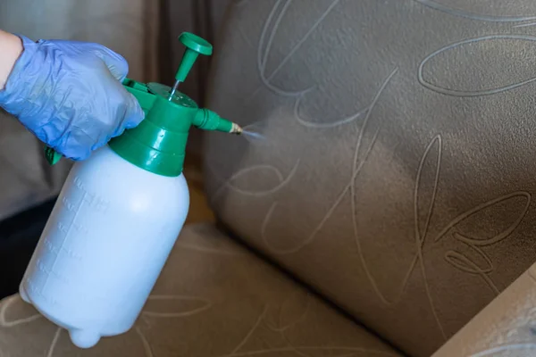 Kapitone kanepe profesyonel ayıklama yöntemi ile temizlik kimyasal closeup. Adam sprey tutuyor.