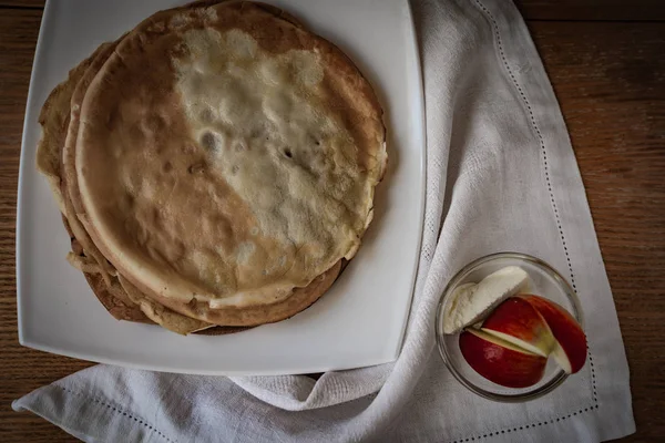 Bovenaanzicht met pannenkoeken in witte plaat en glas voor icecream met drie segmenten van rode appel — Stockfoto