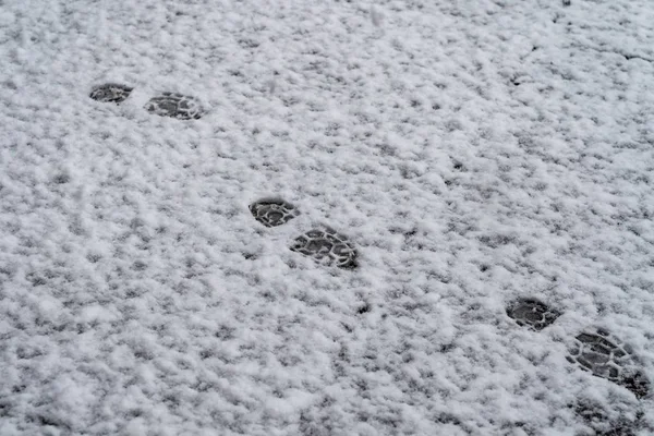 Fußspuren im Schnee auf dem Bürgersteig — Stockfoto