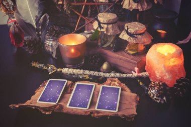 3 Tarot kartı sihirli eşyalarla birlikte siyah bir masaya yayılmış. Soğuk renklere bürünmüş