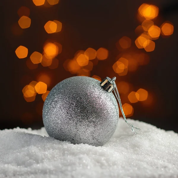 Christmas tree ball on a snow with garlands on a background with bokeh effect