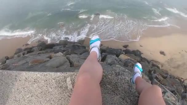 Patas femeninas con vista al Océano Atlántico. Playa vacía en Povoa de Varzim, Portugal en el día de otoño brumoso con olas que se estrellan en la orilla y niebla en la distancia . — Vídeos de Stock